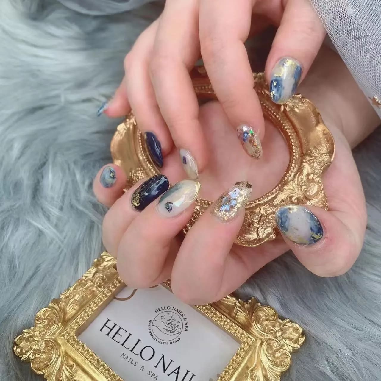 Navy marble nails with gold foil and glitter accents at Hello Nails & Spa